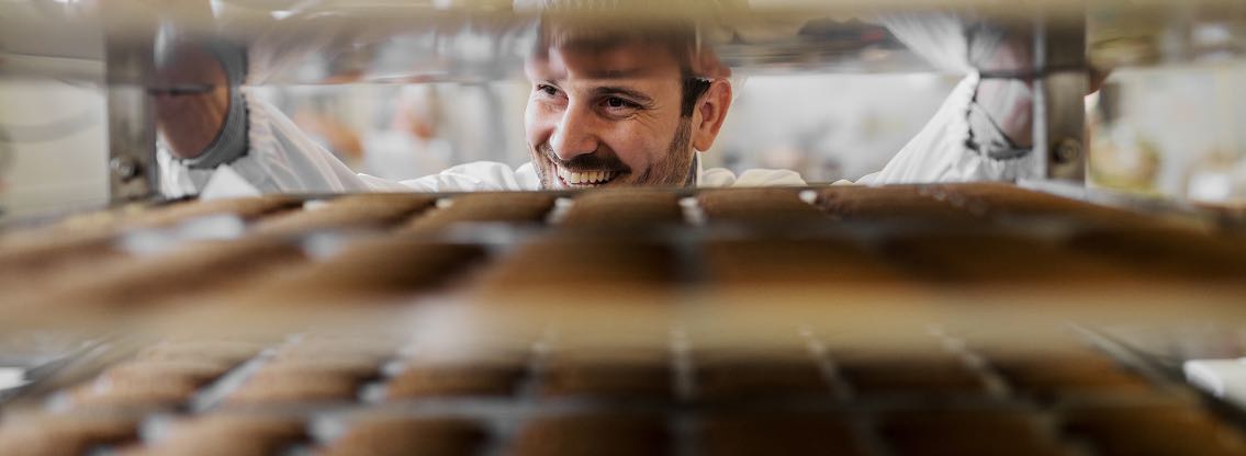 baker putting bread in oven